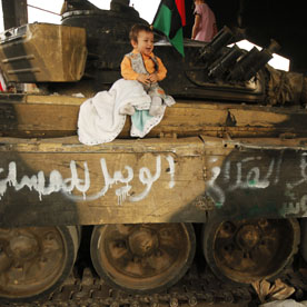 A Libyan boy smiles to his father as he sits on a destroyed tank belonging to forces loyal to Muammar Gaddafi (May 22nd, Reuters)