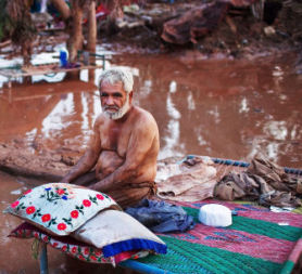 A man sits with his belongings in the mud after the flood. (Getty)
