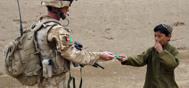 A British soldier gives a pen to an Afghan boy during a patrol in the streets of Showal in Nad-e-Ali district. (Getty)