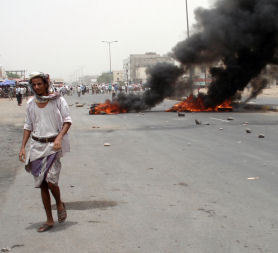 Yemeni man walks past burning tyres during a protest in the southern town of Sabr. (Getty)