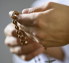A hand holding rosary beads in prayer (Getty)