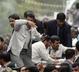 Bodyguards react after the sound of an explosion behind the entourage of Iranian President Ahmadinejad as he is welcomed to Hamadan (Credit: Reuters)