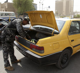 A policeman searches a car at a checkpoint in al-Sa&apos;adoun street in Baghdad. Reuters.