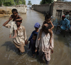A family wades through waters to flee from the flooded village of Karam Pur