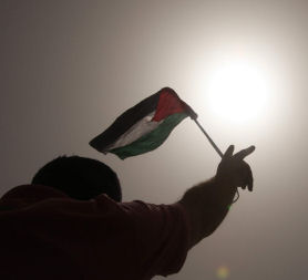 A Palestinian protester holds a flag - before Israel and Palestinian officials are invited to resumee peace talks in Washington (Credit: Reuters)