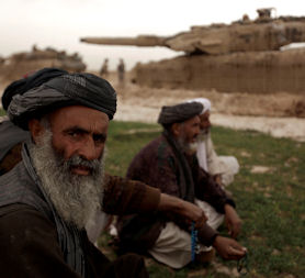 Afghan farmers sit next to a Danish tank near Marjah (Getty)
