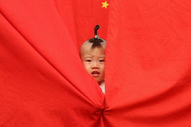 A child wraps themselves in the Chinese flag
