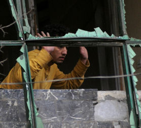 man raises his hands as the prepares to escape a nearby gun battle in Kabul. (Credit: Getty)